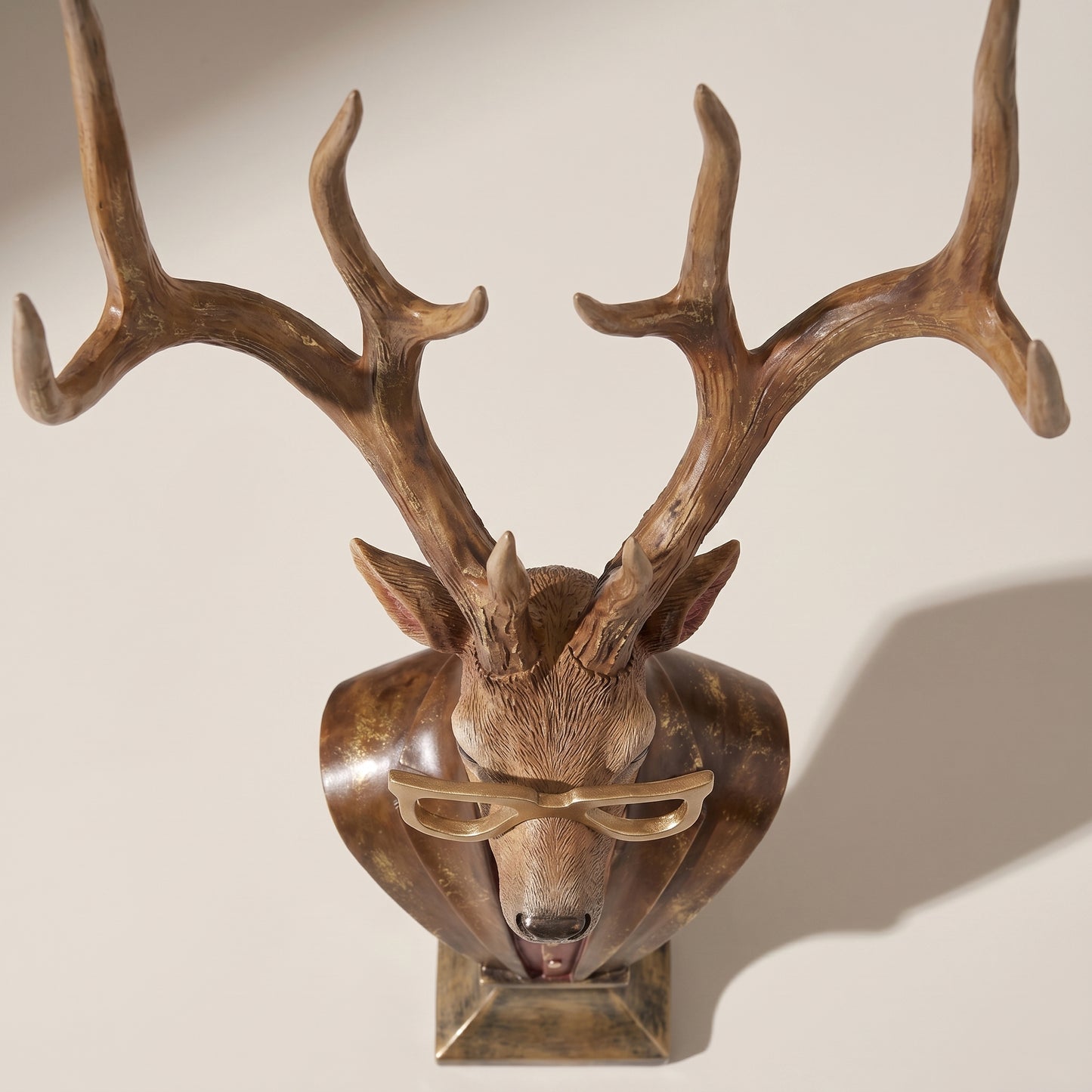 Busto de ciervo de resina sobre pedestal con gafas